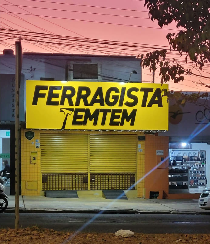 Fachada da Ferragista TemTem, letreiro amarelo aceso ao entardecer, no Setor Novo Horizonte em Goiânia
